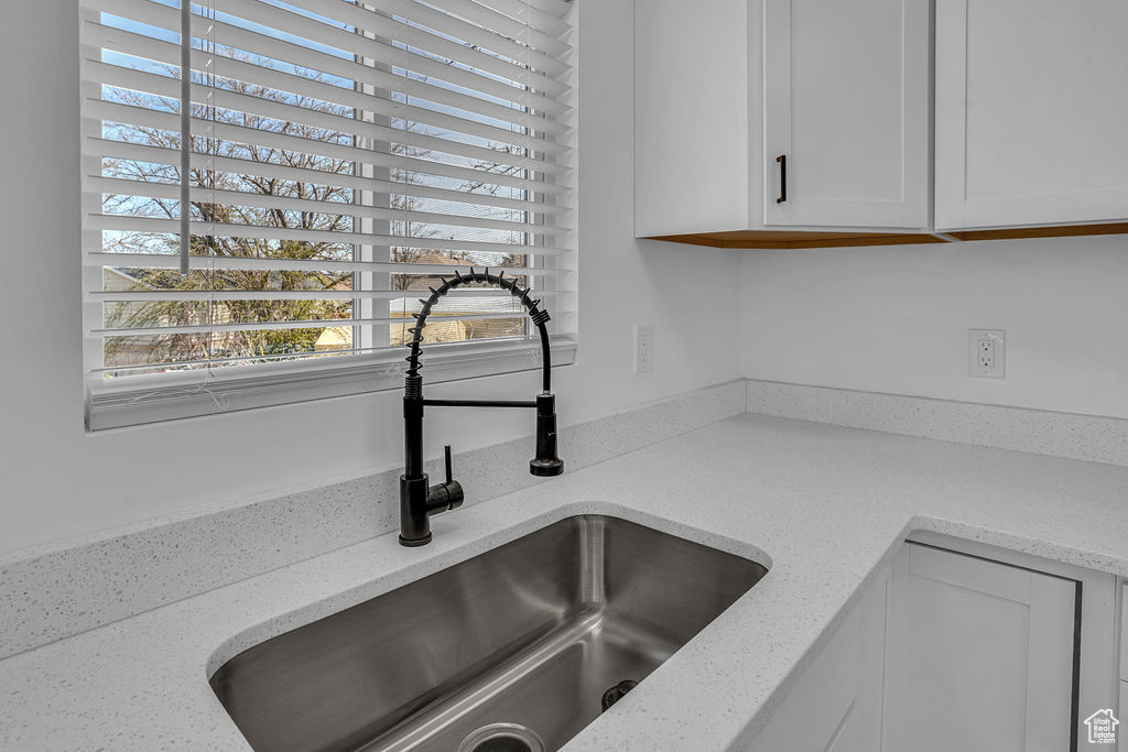 Details with light stone countertops, white cabinetry, and a sink