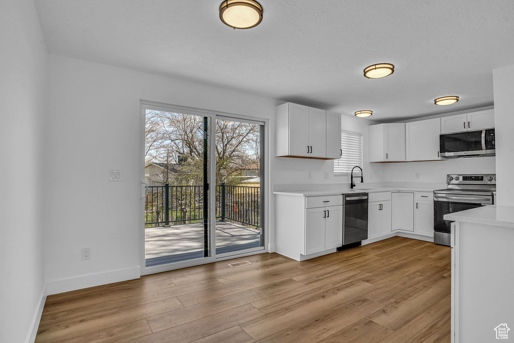 Kitchen featuring a sink, light countertops, appliances with stainless steel finishes, and light wood finished floors
