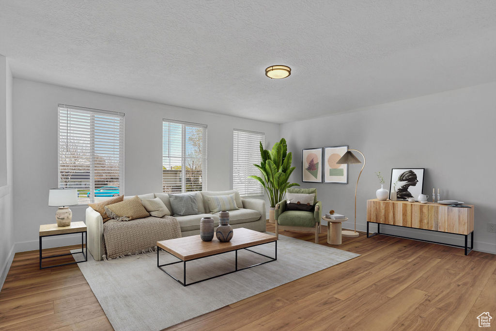 Living area with baseboards, wood finished floors, and a textured ceiling