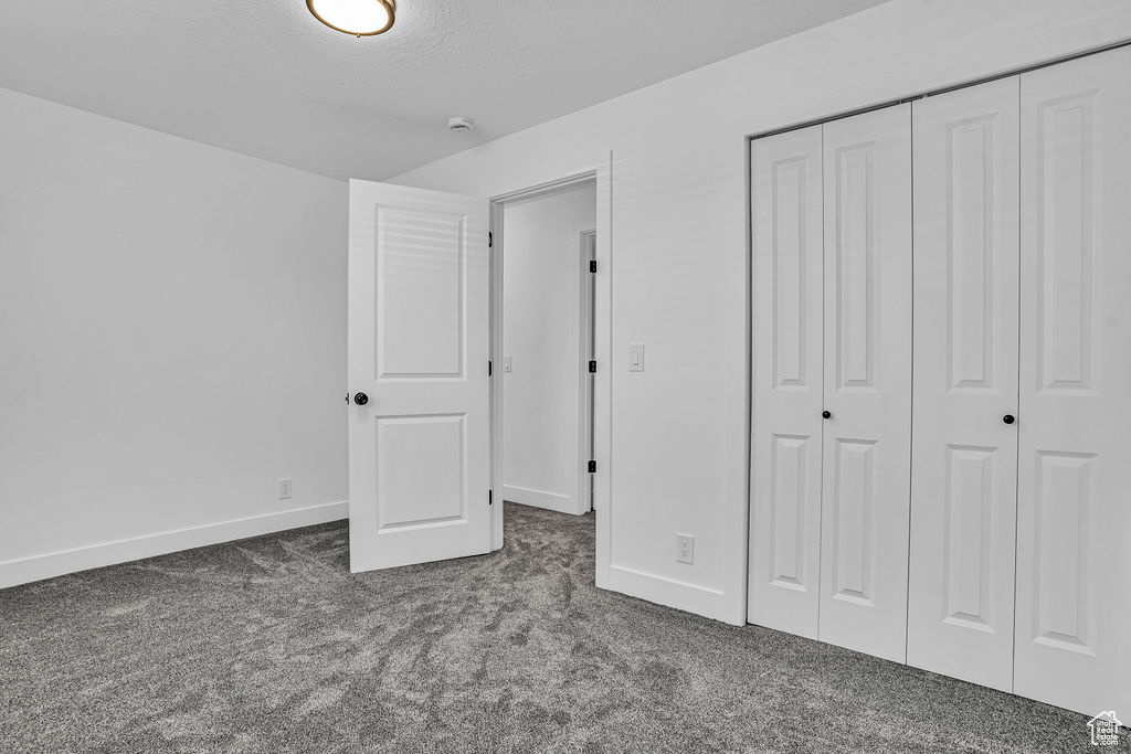 Unfurnished bedroom featuring carpet flooring, a closet, baseboards, and a textured ceiling