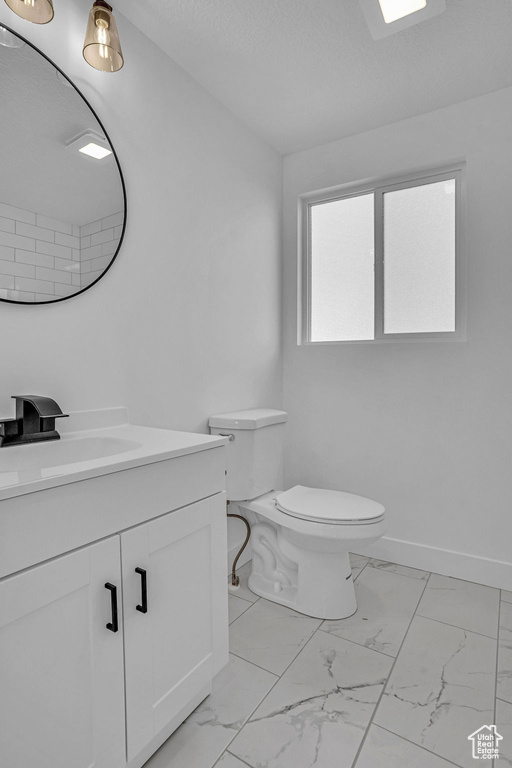 Bathroom featuring vanity, baseboards, a textured ceiling, toilet, and marble finish floor