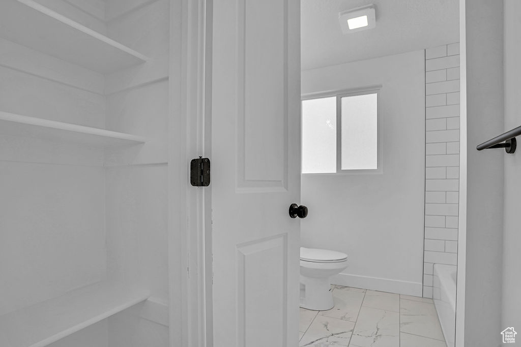 Full bathroom featuring marble finish floor, baseboards, and toilet