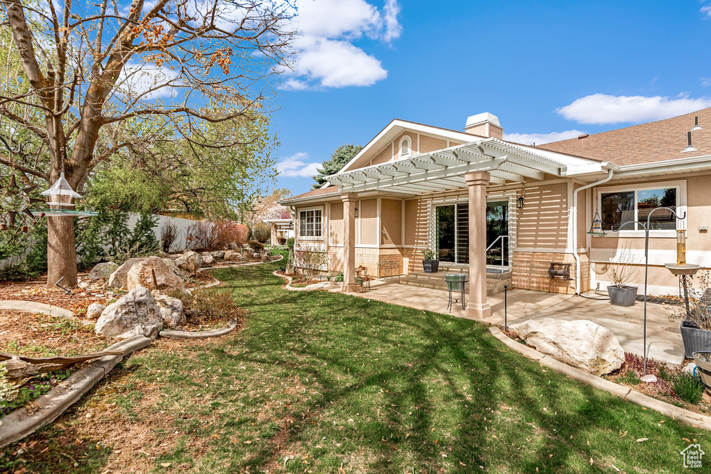 Rear view of property with a pergola, a chimney, a patio, brick siding, and a yard