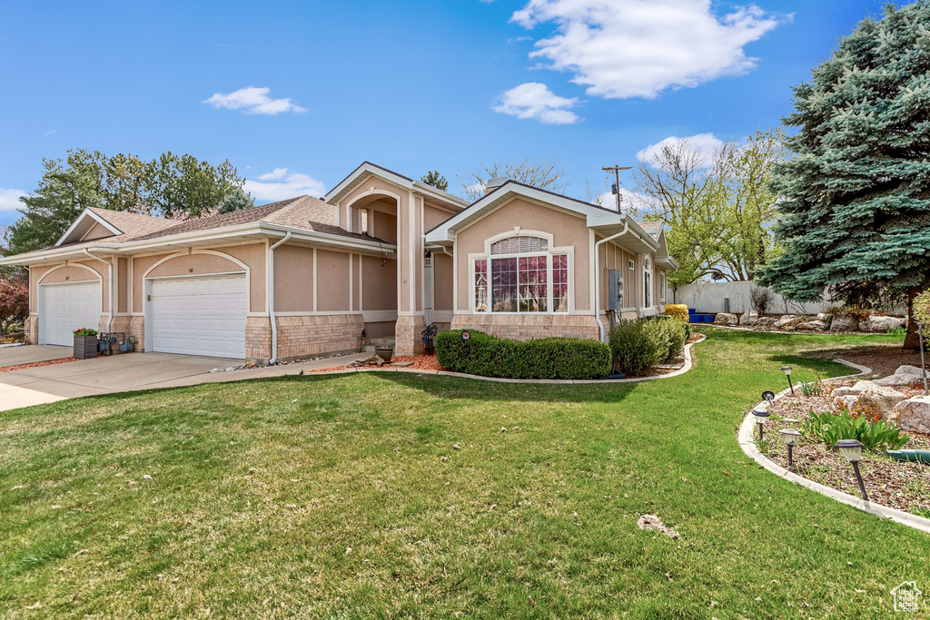 Single story home featuring a garage, driveway, a front yard, and stucco siding