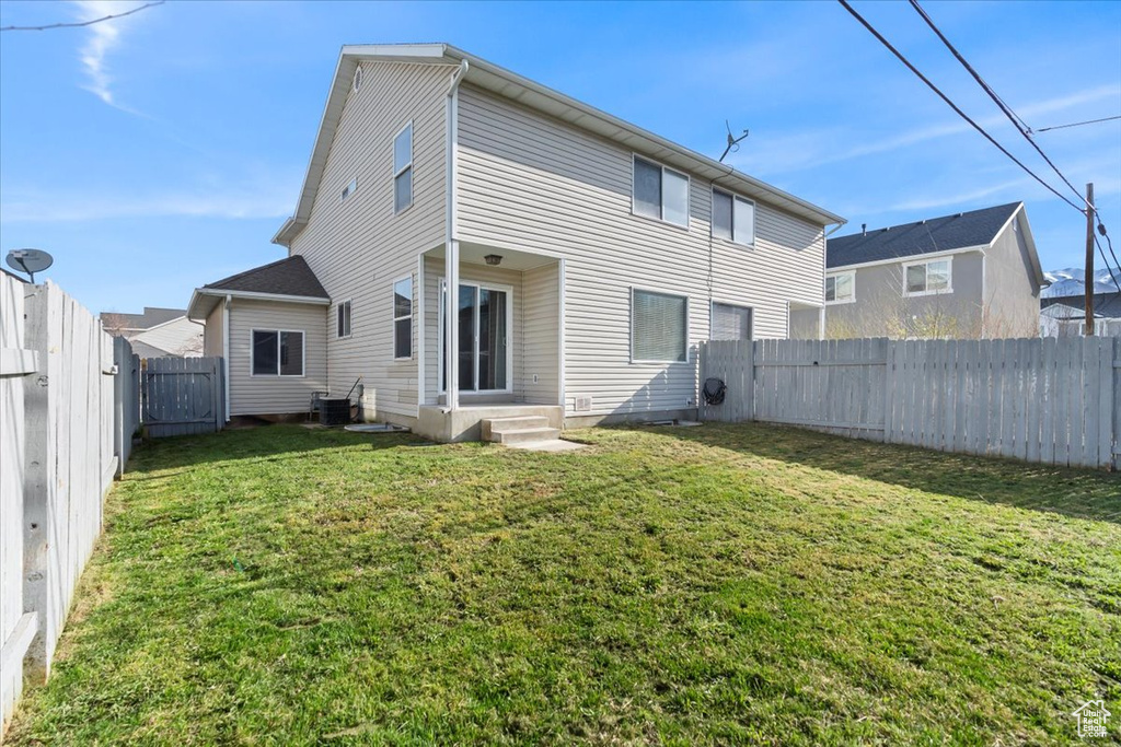 Back of house featuring a yard, entry steps, a fenced backyard, and cooling unit