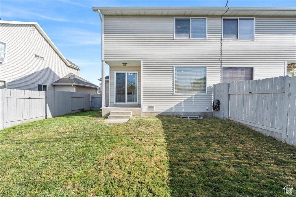 Back of house with a yard, entry steps, and a fenced backyard