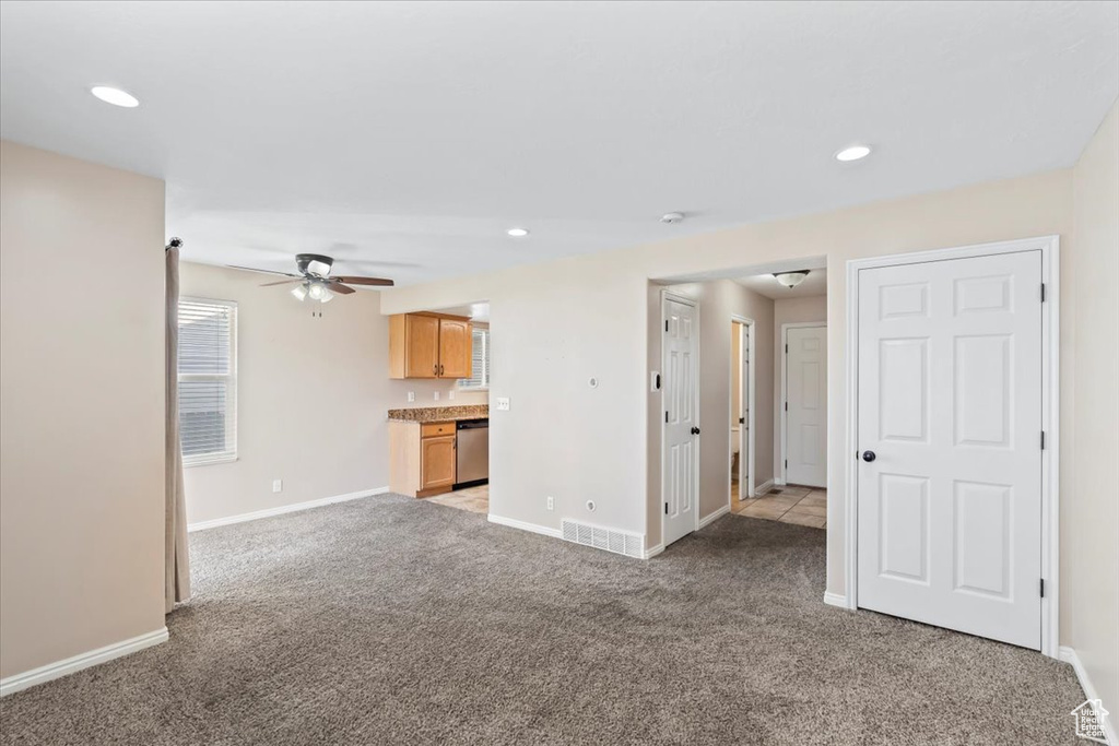 Unfurnished living room with light carpet, visible vents, baseboards, and ceiling fan