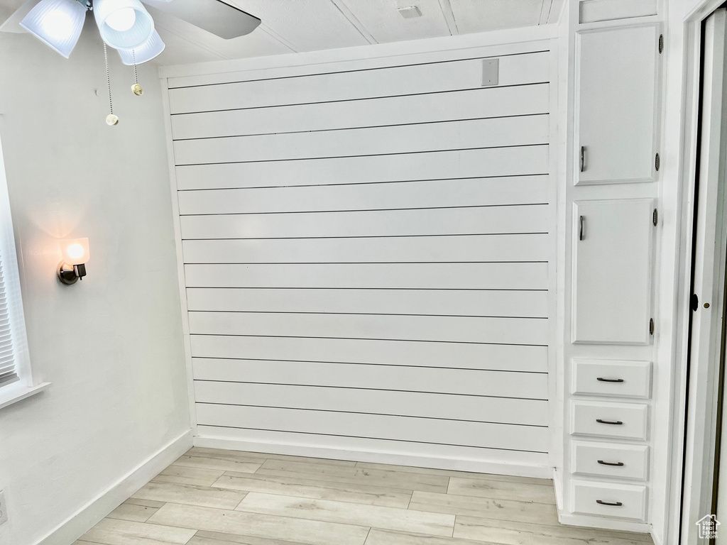 Room details with wood finished floors, wood walls, baseboards, and a ceiling fan