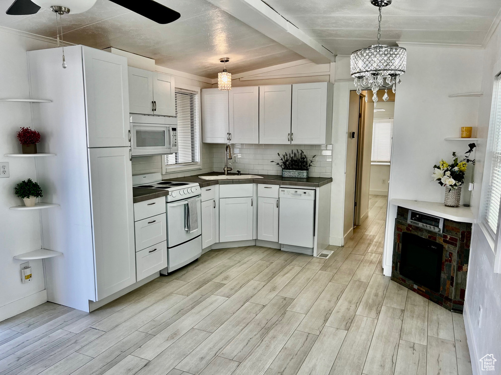 Kitchen with tasteful backsplash, white appliances, light wood-style floors, and a sink