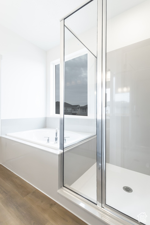 Bathroom with a shower stall, a bath, and wood finished floors