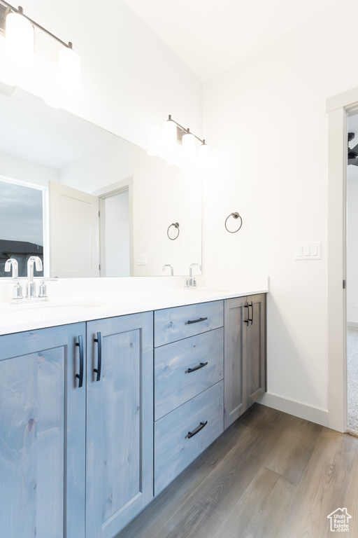 Bathroom with baseboards, a sink, double vanity, and wood finished floors