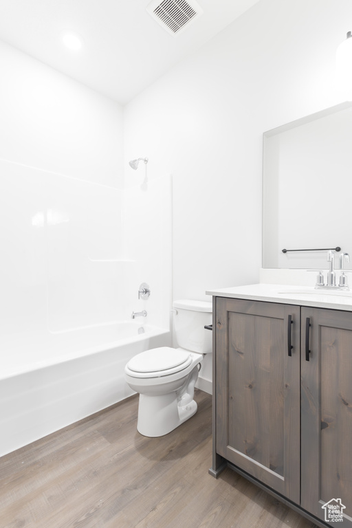 Full bath with visible vents, toilet, vanity, wood finished floors, and bathing tub / shower combination