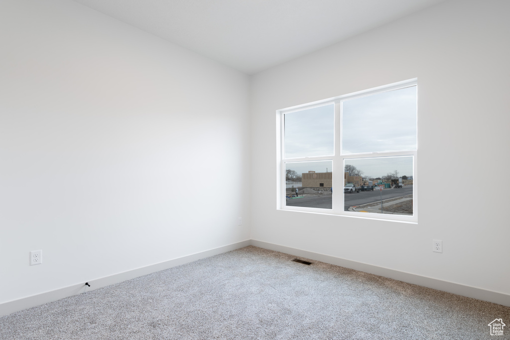 Unfurnished room with carpet flooring, baseboards, and visible vents