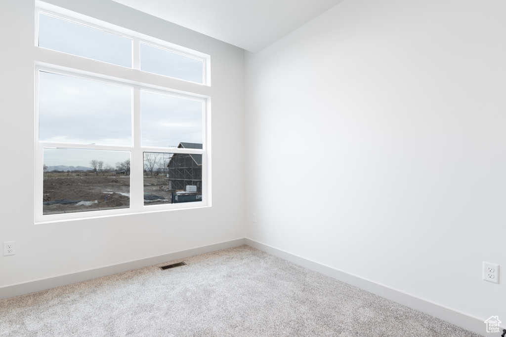 Spare room with carpet flooring, baseboards, lofted ceiling, and visible vents