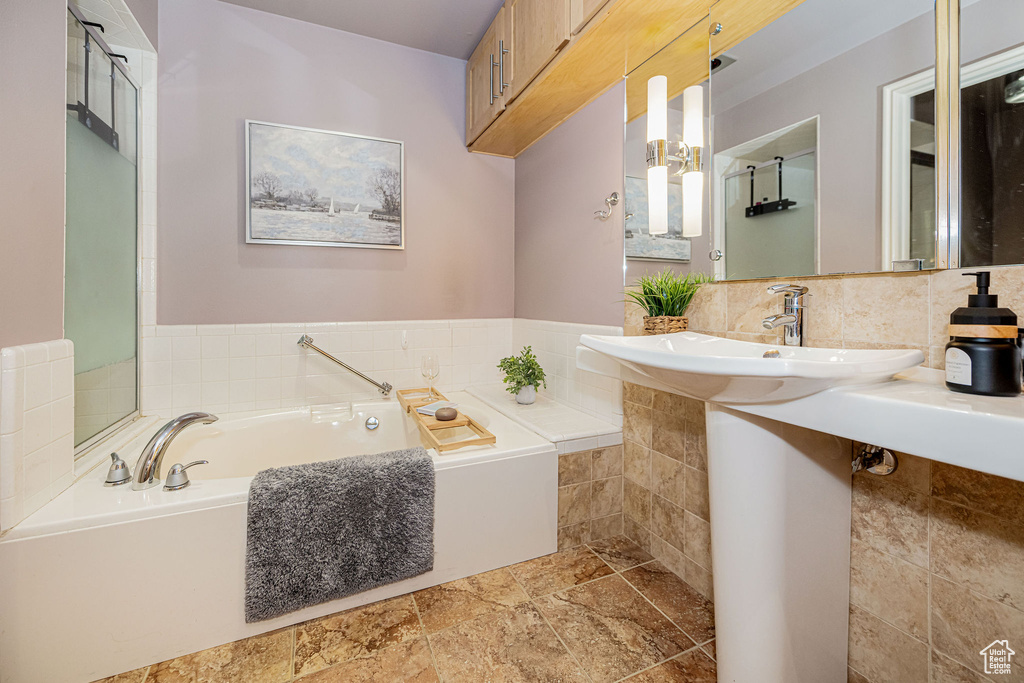 Full bath with a bath, stone tile floors, and tasteful backsplash