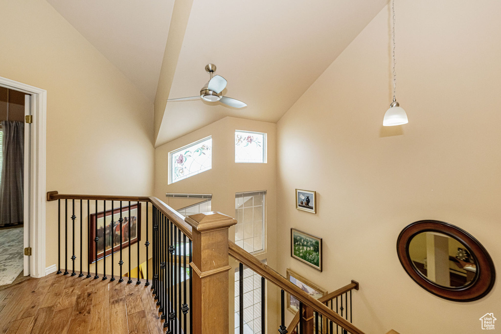 Stairway featuring wood finished floors, high vaulted ceiling, and ceiling fan