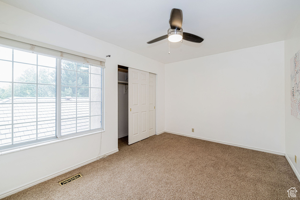 Unfurnished bedroom featuring carpet floors, a closet, and ceiling fan