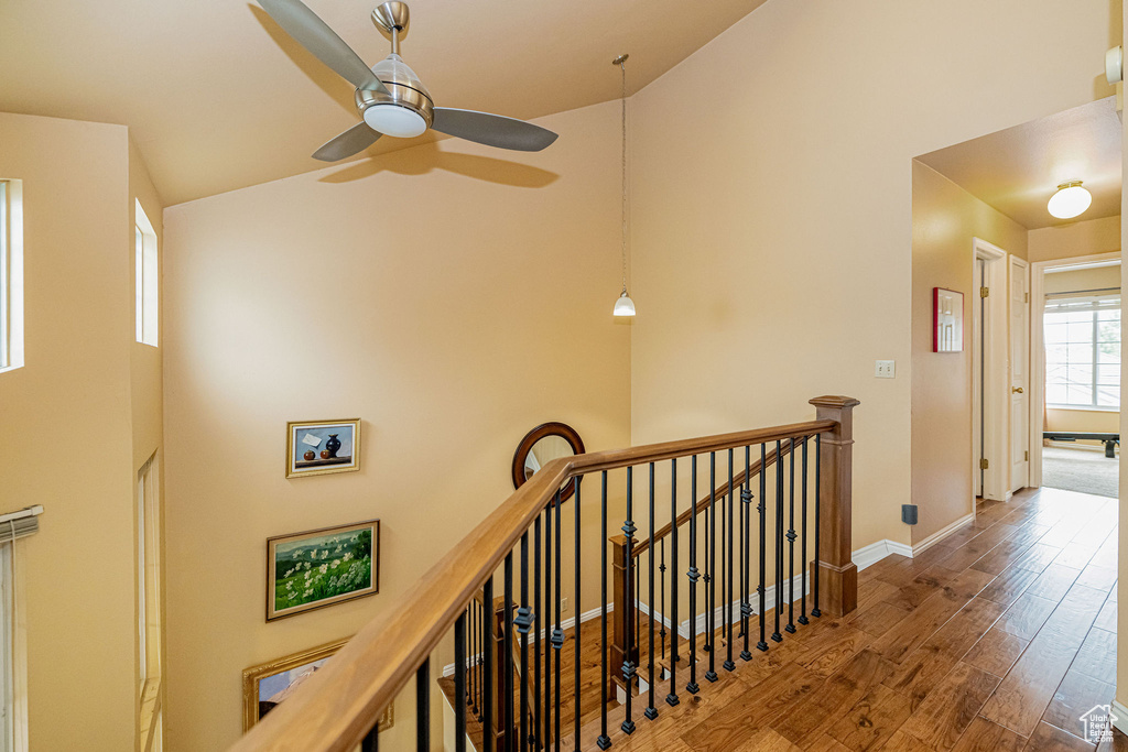 Corridor featuring an upstairs landing, high vaulted ceiling, and wood finished floors