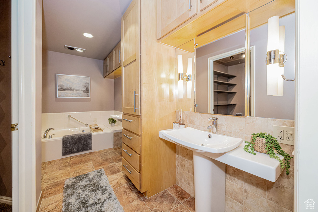 Full bath with a bath and decorative backsplash