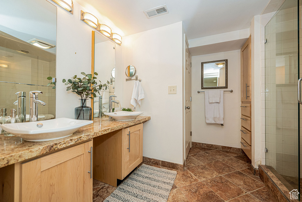 Full bathroom with double vanity and tiled shower