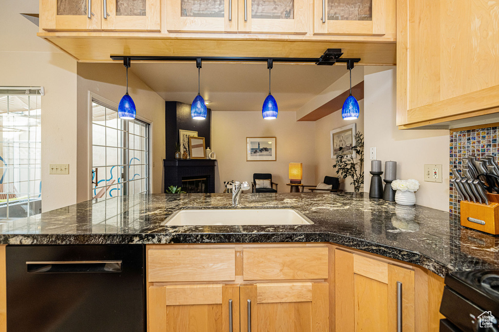 Kitchen featuring dishwashing machine, light brown cabinetry, decorative light fixtures, open floor plan, and range