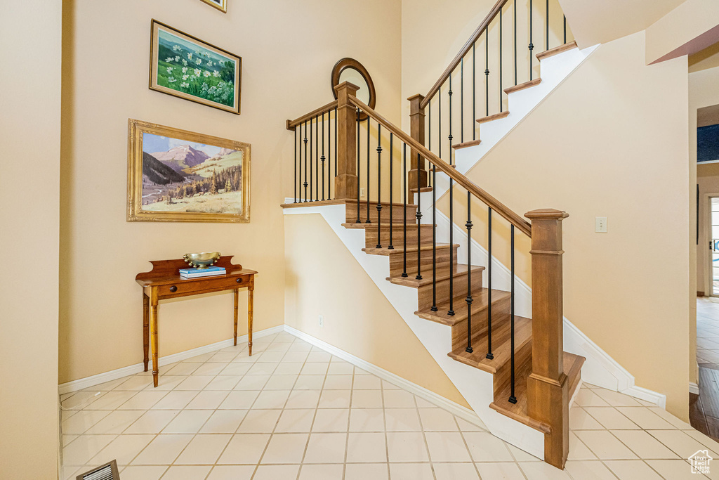 Staircase featuring tile patterned floors and a towering ceiling