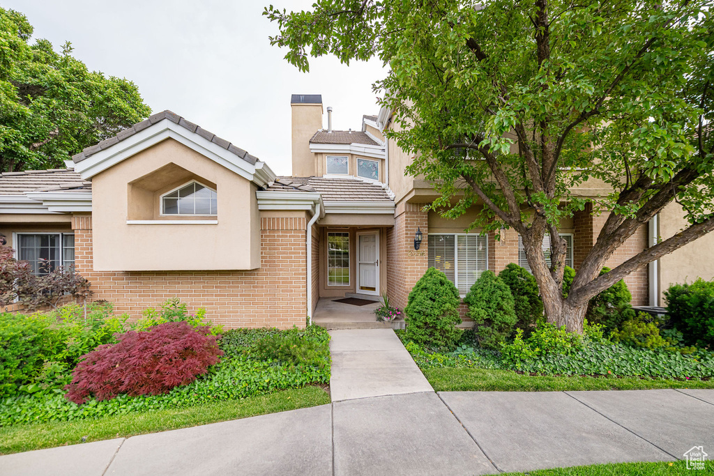 View of front of property featuring brick siding, stucco siding, and a tile roof