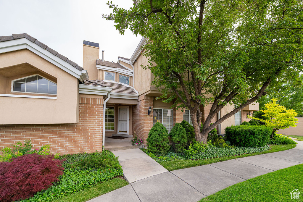 View of front of property featuring stucco siding, brick siding, and a tile roof