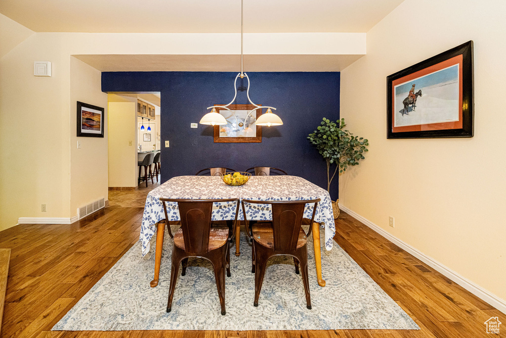 Dining area with an accent wall and wood finished floors
