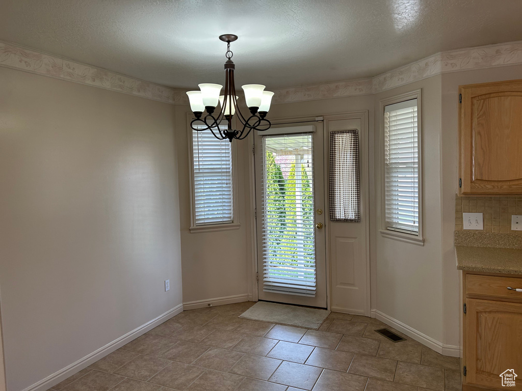 Doorway to outside featuring an inviting chandelier, baseboards, and visible vents