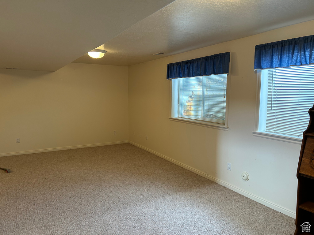 Unfurnished room with a textured ceiling, baseboards, and carpet