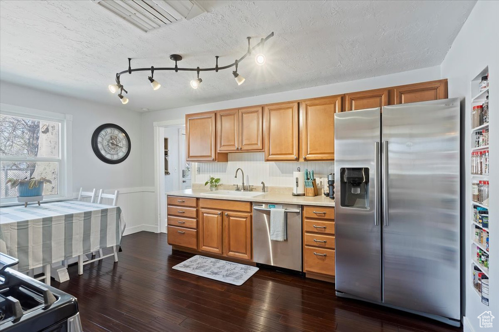 Kitchen with dark wood-style floors, a textured ceiling, light countertops, appliances with stainless steel finishes, and a sink