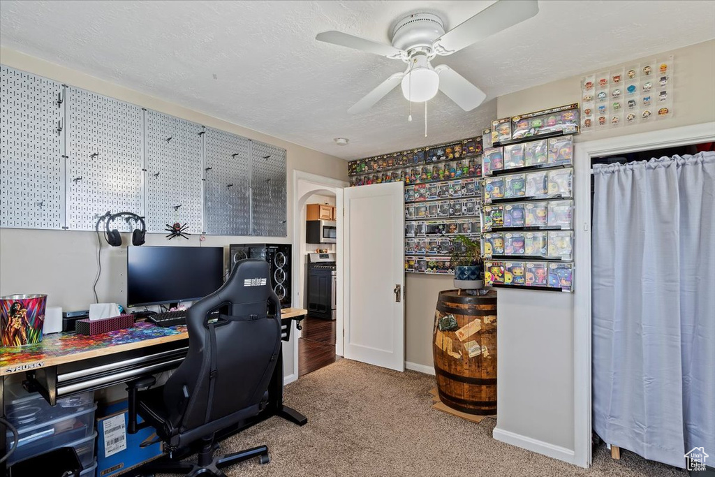 Carpeted home office with ceiling fan, baseboards, and a textured ceiling