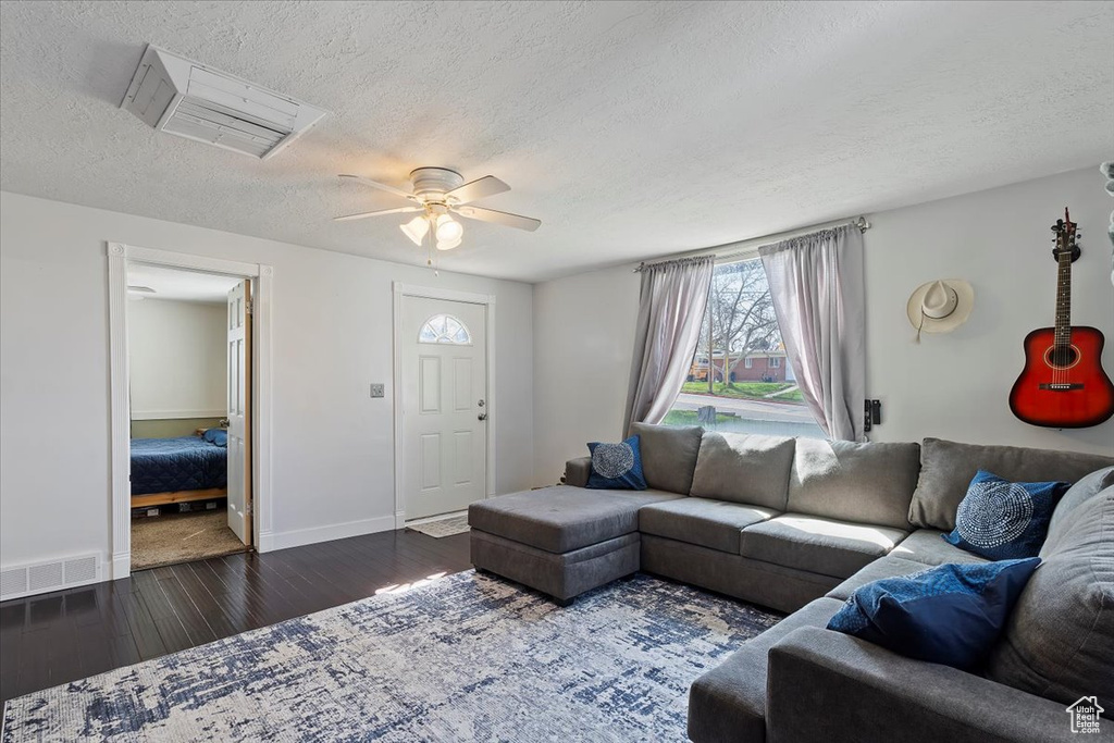 Living area with visible vents, ceiling fan, wood finished floors, and a textured ceiling
