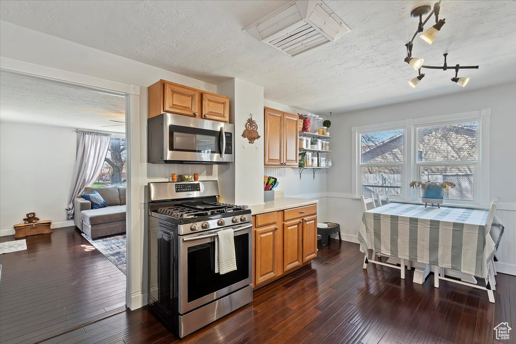 Kitchen featuring dark wood-style flooring, light countertops, a textured ceiling, and stainless steel appliances