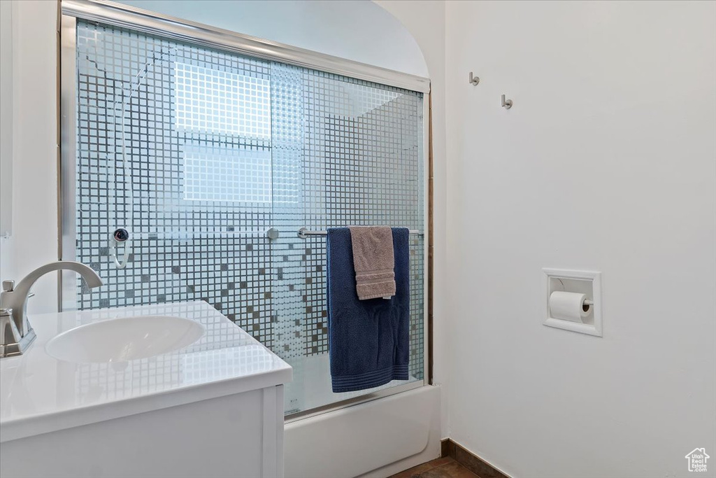 Bathroom with baseboards, vanity, and shower / bath combination with glass door