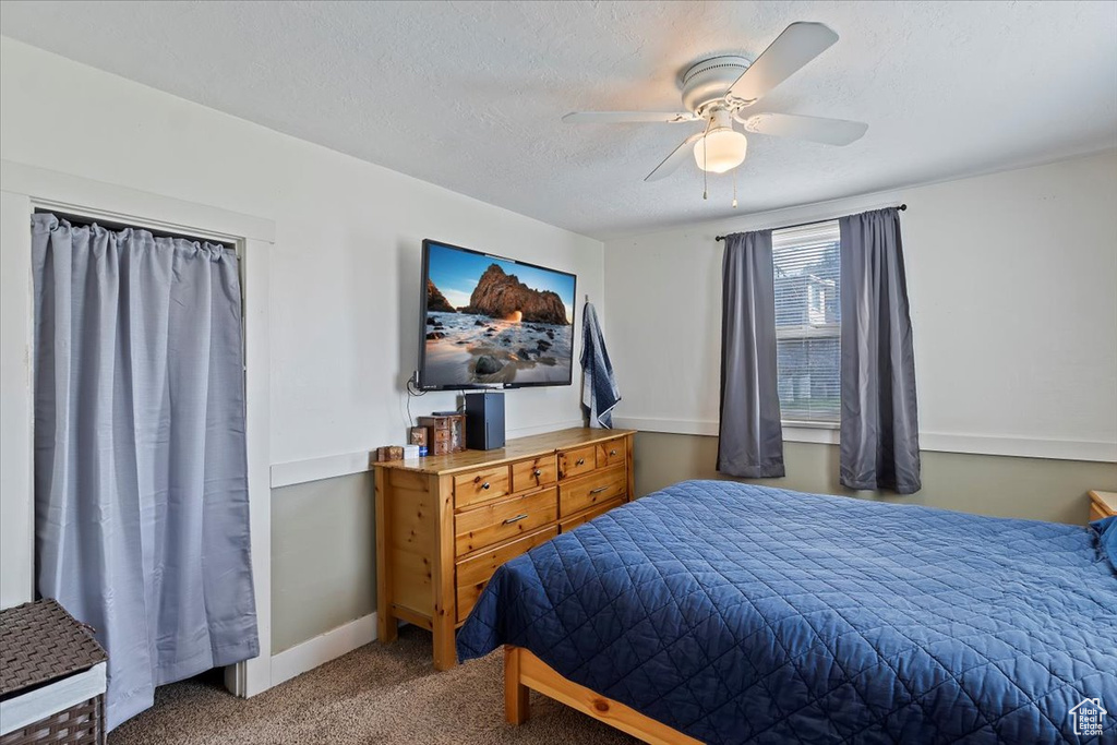 Bedroom featuring ceiling fan, carpet, baseboards, and a textured ceiling