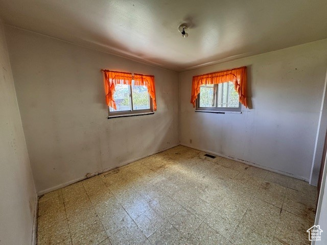 Empty room with visible vents, tile patterned floors, and a healthy amount of sunlight