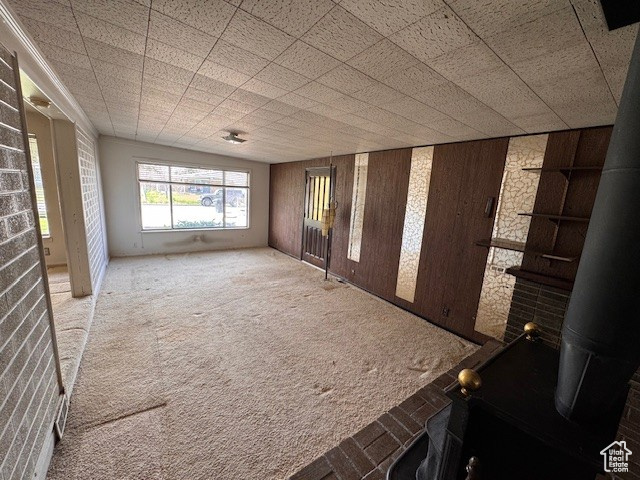 Spare room featuring carpet floors, a wood stove, and wood walls