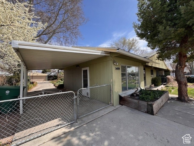 View of side of property featuring a carport, fence, and a gate