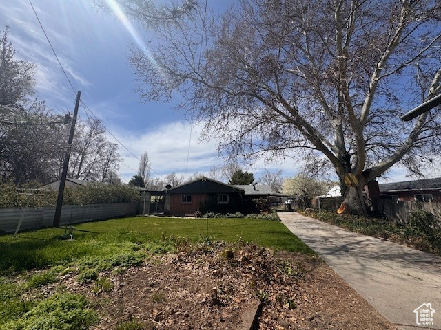 View of yard featuring fence and driveway