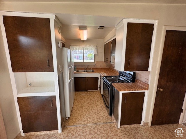 Kitchen with fridge with ice dispenser, dark brown cabinets, a sink, light countertops, and black range with electric cooktop