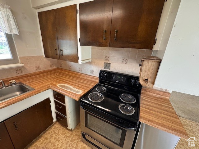 Kitchen with a sink, light countertops, decorative backsplash, and stainless steel range with electric cooktop