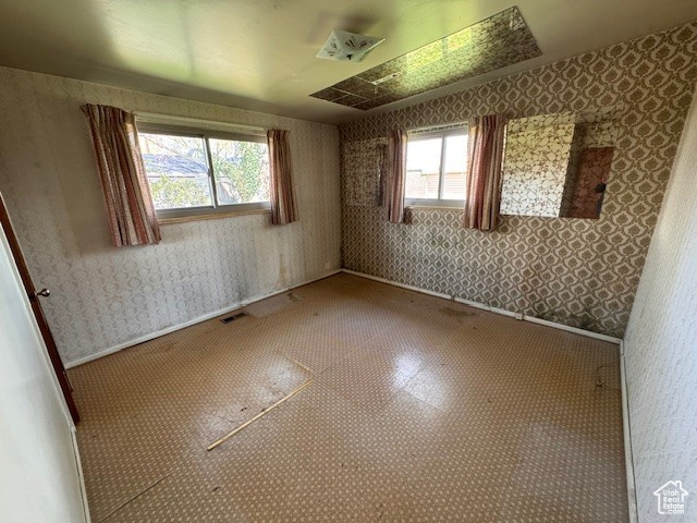 Spare room featuring visible vents, baseboards, and wallpapered walls