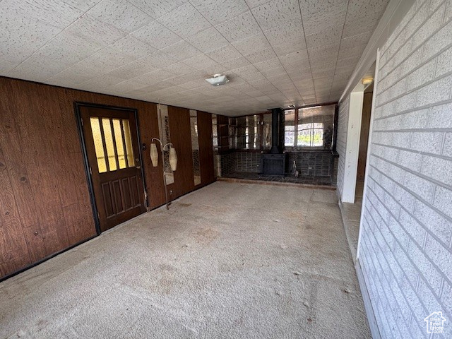 Interior space with a wood stove, wooden walls, and carpet