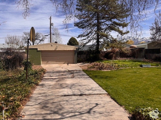 View of yard with driveway, fence, and an outdoor structure