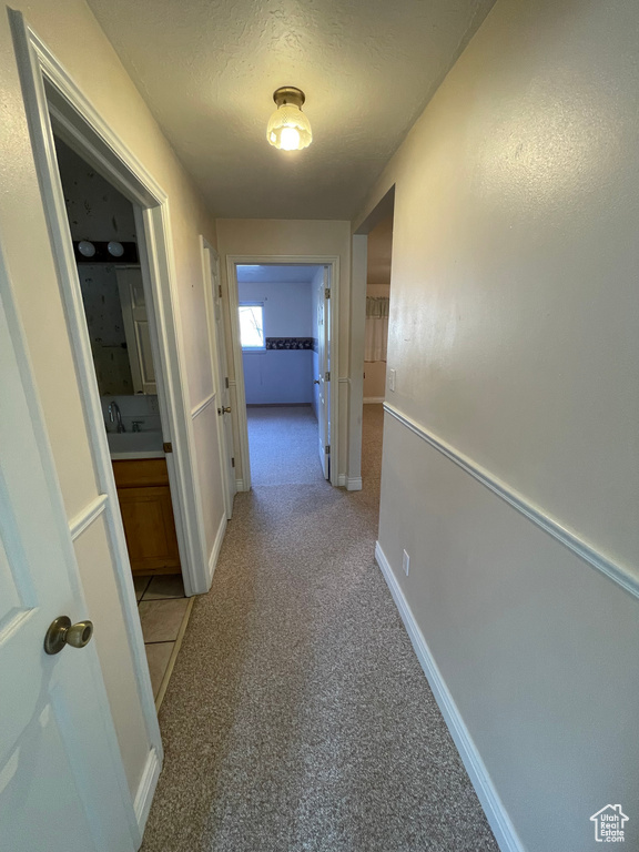 Hall with baseboards and a textured ceiling