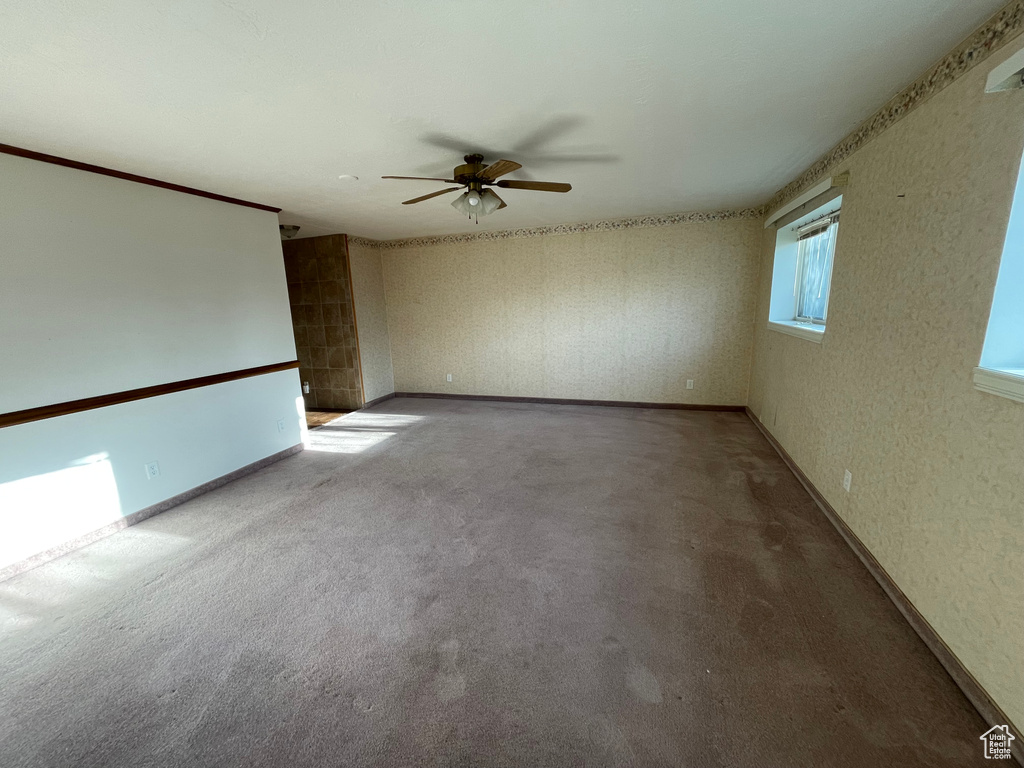 Empty room with carpet floors, ceiling fan, and baseboards