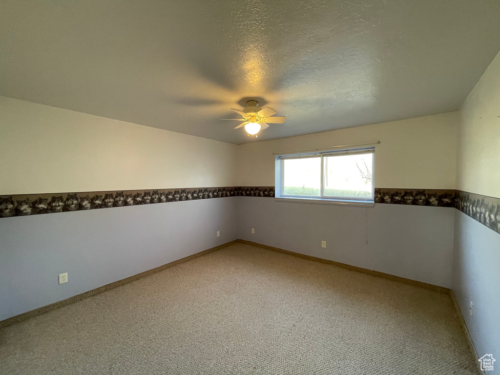 Spare room featuring ceiling fan, light carpet, and baseboards