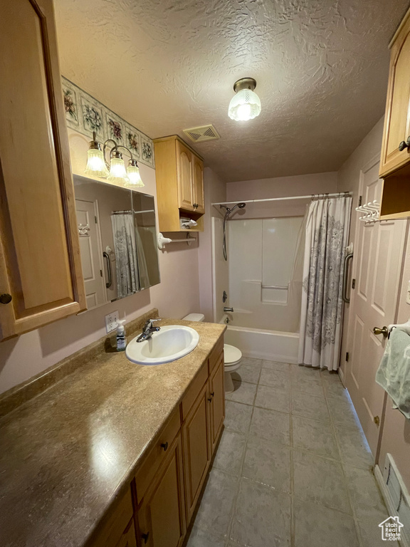 Full bathroom with vanity, a textured ceiling, toilet, visible vents, and shower / bath combo with shower curtain